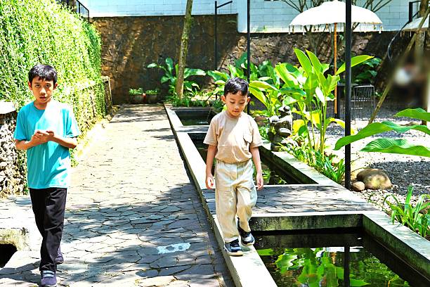 Two kids walking on stone pathway in outdoor natural garden environment.