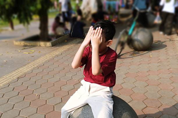 prepubescent boy with his hand on his ear with a gesture of not hearing well. with red t-shirt