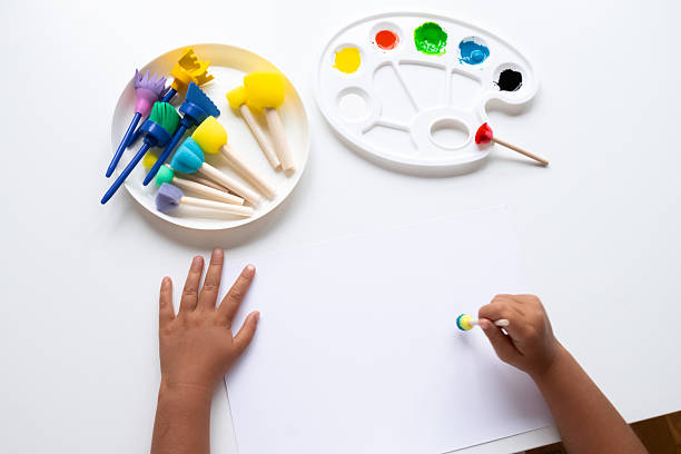 istock Child painting with colorful brushes and palette on white surface 2231390917