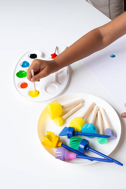 istock Child painting with colorful brushes and palette active creativity at work 2231390922