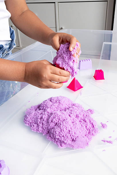 istock Child playing with purple kinetic sand indoors 2231390923