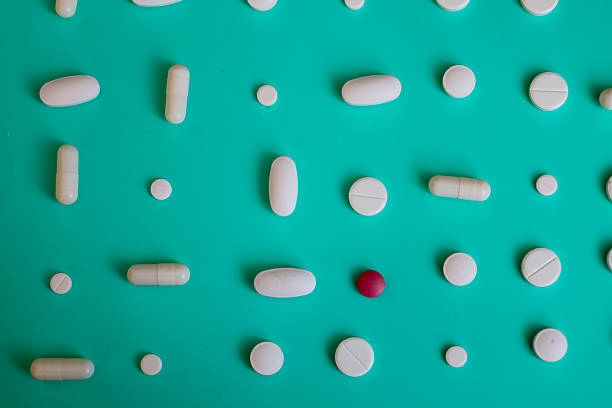 istock White pills and capsules, along with one red pill, are arranged on a vibrant turquoise background, symbolizing medicine and pharmaceuticals. This ordered composition of various shapes creates a visually appealing and clean image, perfect for illustrating 2231391642