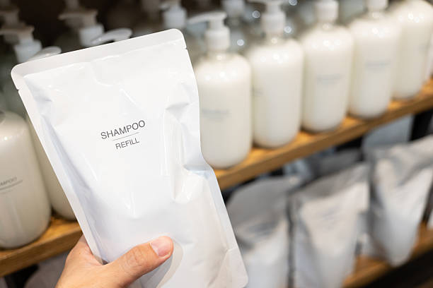istock Hand Holding Shampoo Refill Pouch with Bottles on Shelf, Eco-Friendly Packaging Concept. Sustainable packaging, zero waste shopping, and eco conscious personal care. 2231393029
