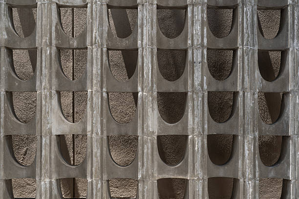 Brutalist Concrete Block Wall Texture. a brutalist style concrete block wall, featuring a repetitive pattern of semicircular openings. architectural, design, and industrial-themed projects.