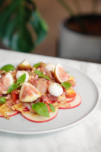 istock Fresh fig and apple salad with mozzarella cheese, pomegranate, and herbs on white plate 2231399843
