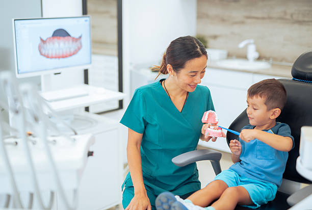 istock Female asian dentist explaining to a small boy about brushing teeth. 2231400095