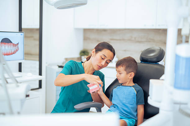 Female asian dentist explaining to a small boy about brushing teeth.
