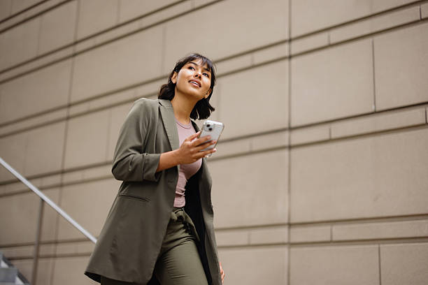 Businesswoman walking up stairs while using her phone