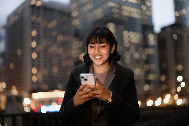 istock Young businesswoman using smartphone in Chicago at night 2231400331