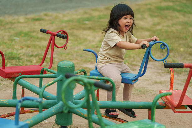 istock toddler girl having fun while playing on carousel at playground 2231412546