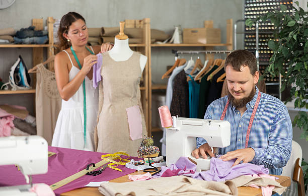 istock Tailor sewing at machine while colleague working with mannequin 2231413658