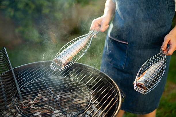 Close-up of Woman making grilled fish on the BBQ.