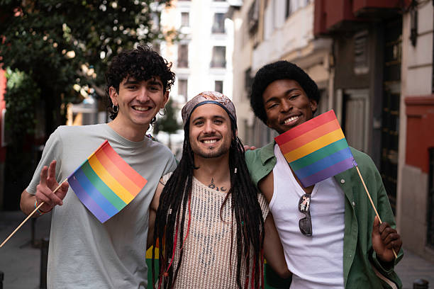 istock Three happy friends celebrating gay pride holding rainbow flags 2231419033