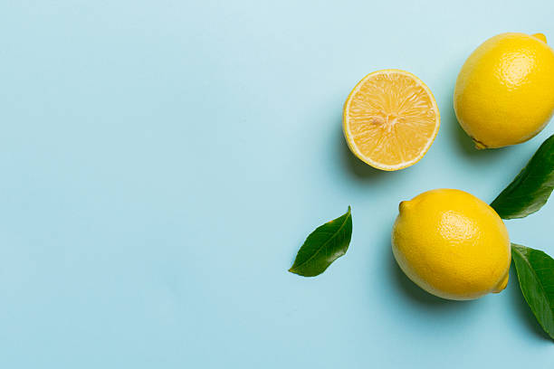 istock Many fresh ripe lemons with green leaves on colored background, top view, space for text 2231420808