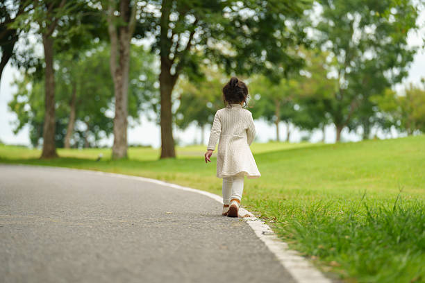 toddler girl walk along a pathway in the park