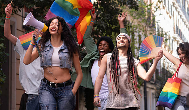 istock Young lgbt people marching for lgbtq+ rights with rainbow flags and megaphone 2231426108