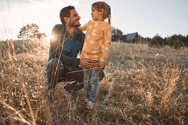 Happy father and daughter spending time in nature. It’s beautiful autumn day. Sunset time.