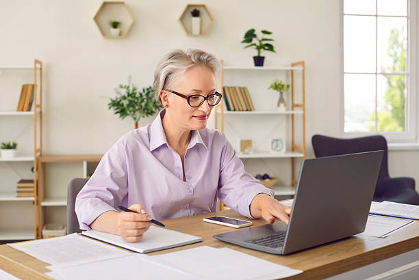 istock Senior business lady is comparing electronic and paper documents while working in her home office. 2231427290