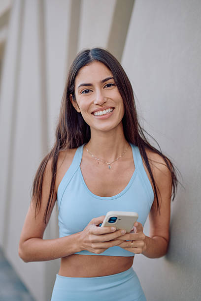 istock Young sporty woman using her smartphone and smiling 2231428293