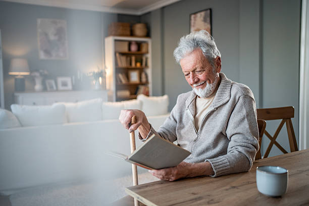 istock Senior man reading a book and smiling at home 2231429497