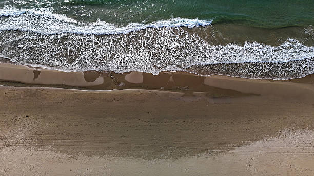 istock Waves softly lap at the sandy shore under a clear sky, creating a tranquil coastal landscape in mid-afternoon sunlight 2231430012