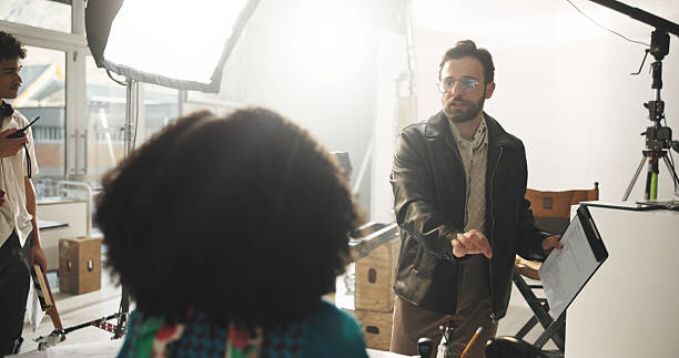 istock Set, man and director with script, talking and explaining scene to actor, entertainment or creative. Production, people and filmmaker with lines for direction, crew and instructions for movie or take 2231431858