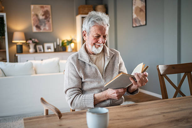 istock Senior man enjoying a book and smiling at home 2231431983