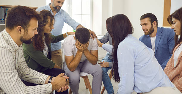 istock People comforting and supporting man who's crying during their group therapy session 2231432916
