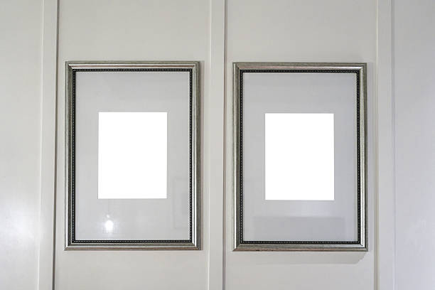 Two mettallic picture frames with blank white center mounted on clean grey panel, mockup interior design presentation