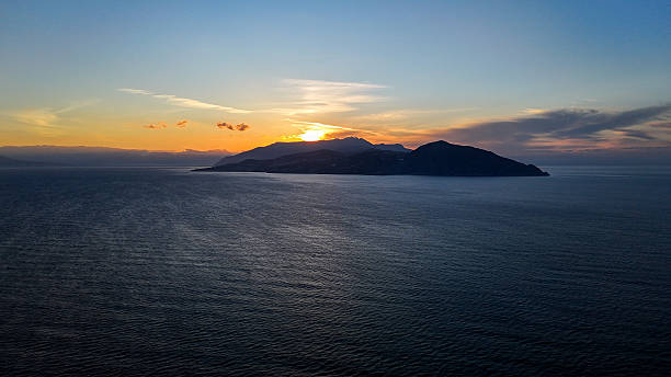 istock Majestic sunset over a tranquil island surrounded by serene waters and distant mountains, painted in hues of orange and purple 2231433609