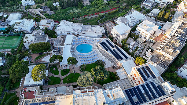 Luxurious hotel complex with sprawling grounds and pristine pool nestled in hillside greenery during golden hour