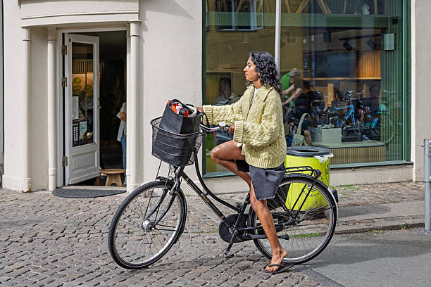 Copenhagen, Zealand, Denmark - August 11th 2025:  A young female cyclist waits patiently at a traffic light in the heart of Copenhagen, where bicycles reign supreme as the city’s preferred mode of transportation. With dedicated bike lanes and a cycling culture woven into daily life, Denmark’s capital showcases how urban mobility can be both efficient and eco-friendly.