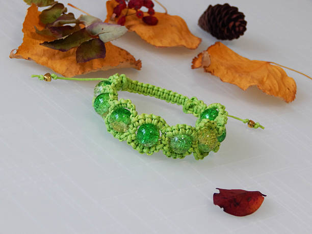 Green friendship bracelet and leafs. Green friendship bracelet on a white