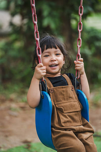 istock cheerful toddler girl playing on swing 2231437002
