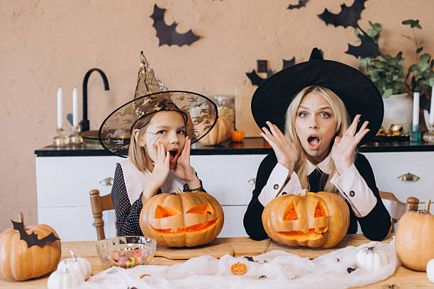 istock Mother and daughter making surprised faces while carving pumpkins for Halloween 2231437268