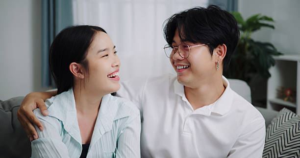 istock Happy Asian couple having fun talking on the sofa at home. 2231440800
