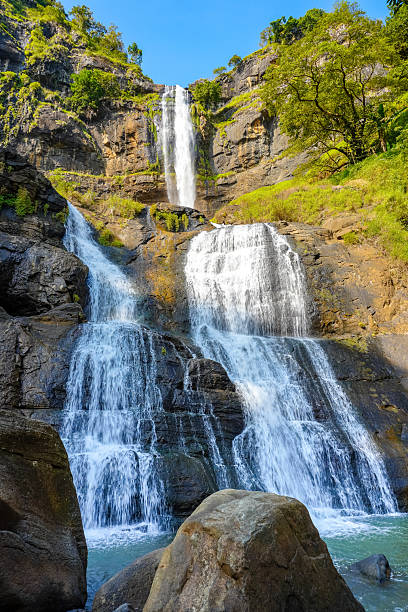istock A tiered waterfall cascades down a rocky cliff, surrounded by lush green trees 2231442109