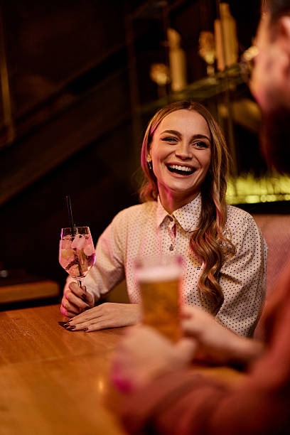 istock Smiling Friends Enjoying Drinks Together at a Cozy Bar Setting 2231442816