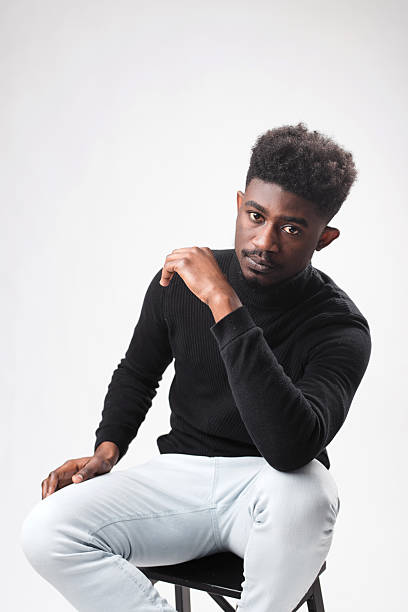 Multiracial handsome brunette man posing in black turtle neck sweater against white background. Successful young man concept. Vertical shot