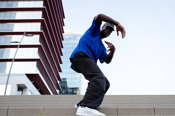 istock Young man showcasing a dynamic street dance routine on steps, surrounded by an urban landscape filled with modern architecture 2231446470
