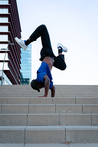 istock Young man breakdancing upside down on concrete steps, showcasing impressive skill and balance against an urban city backdrop 2231446565