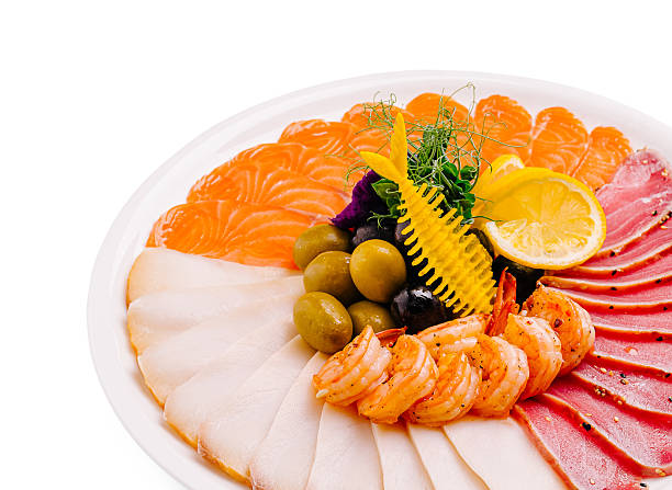 A beautifully arranged seafood platter showcases an assortment of sashimi, including salmon, shrimp, and tuna. Garnished with olives and lemon, it offers a vibrant culinary presentation.