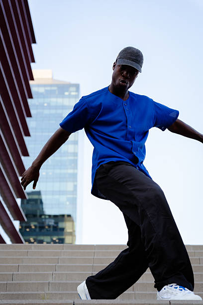 istock Urban breakdancer performing dynamic move, blue shirt and black pants highlighting athletic skill against concrete background 2231446949