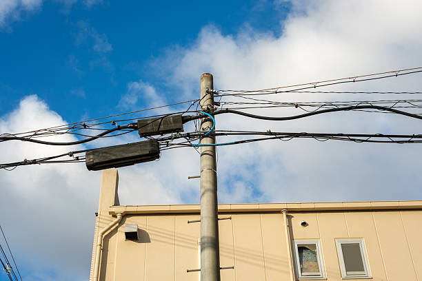 Low angle view of electrical wires from a utility pole and overcast sky.