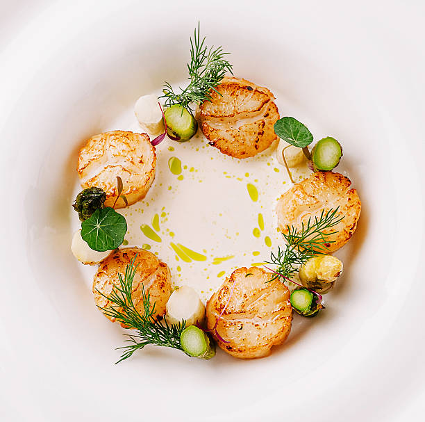 istock Creative culinary presentation with scallops and herbs on a white plate 2231447395