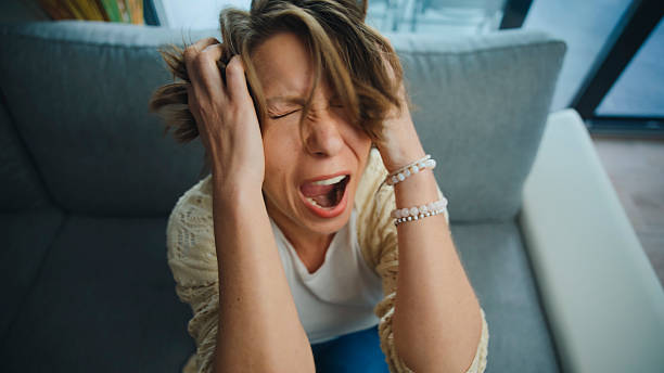 istock Stressed Young Woman Pulling her Hair and Screaming on the Sofa 2231449332