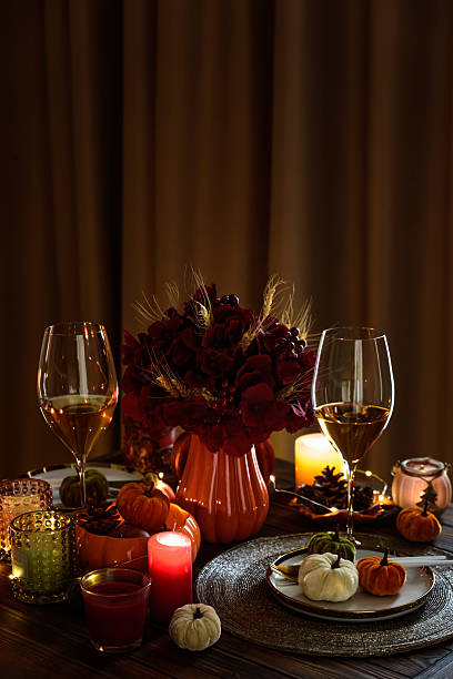 Thanksgiving table setting with decorative pumpkins, candles and string lights on dark wooden table