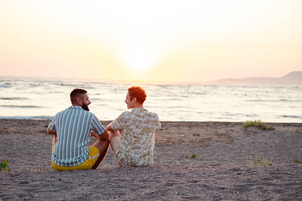 istock Two men enjoying a peaceful sunset on the beach together 2231453376