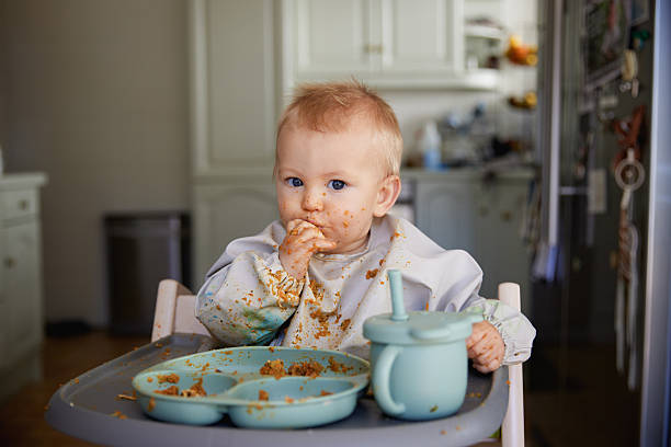 istock Messy Baby Eating with Fingers in Bib 2231453832