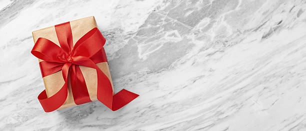 istock Gift box with red bow ribbon, christmas present on marble table background, top view 2231454849
